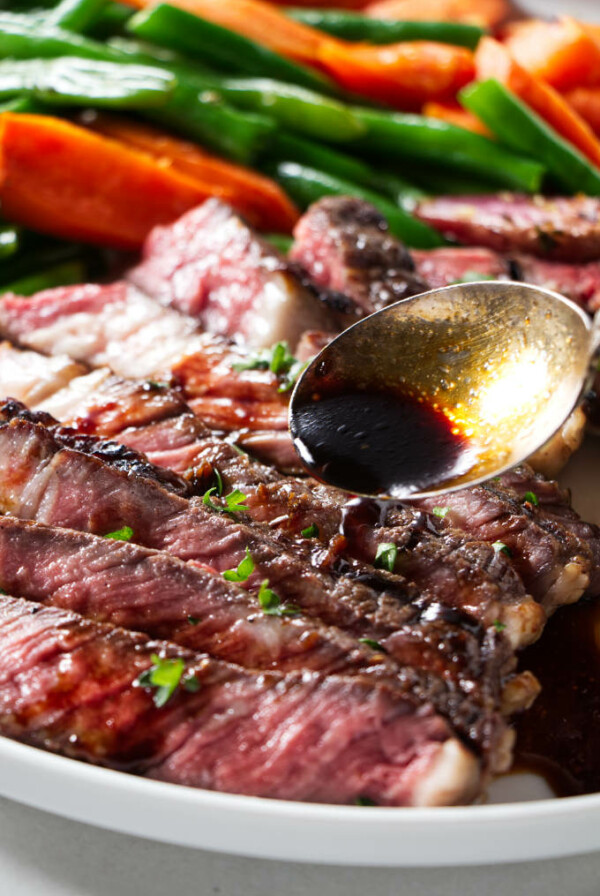 Drizzling sake marinade over a grilled ribeye steak.