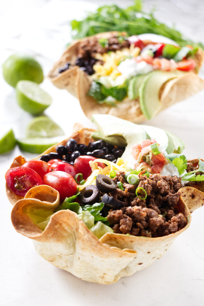 Two taco salad bowls made with ground beef.