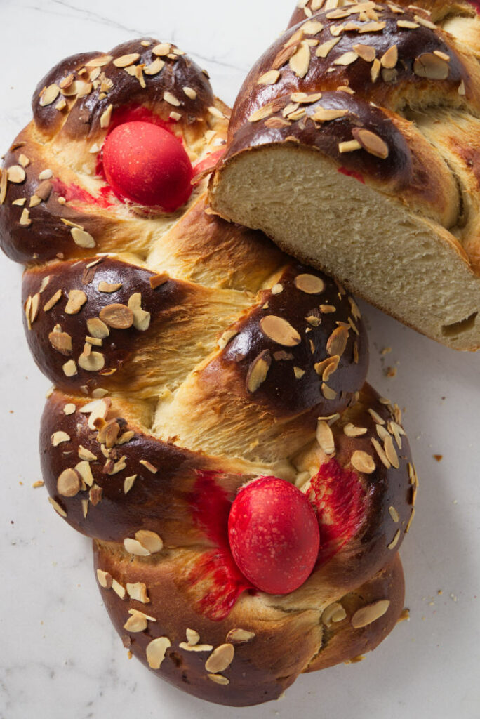 Two loaves of Greek Easter bread with red eggs.