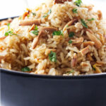 A bowl of basmati rice pilaf with almonds mixed in.