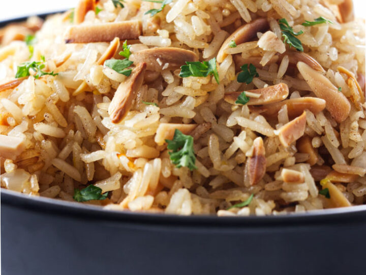 A bowl of basmati rice pilaf with almonds mixed in.