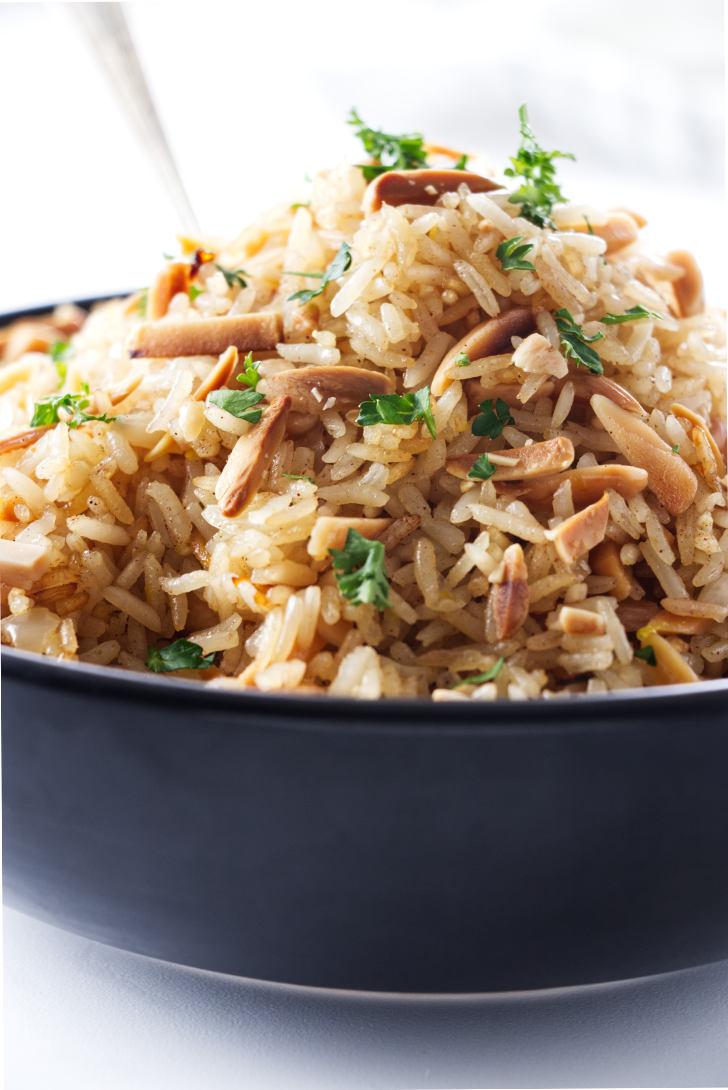 A bowl of basmati rice pilaf with almonds mixed in.
