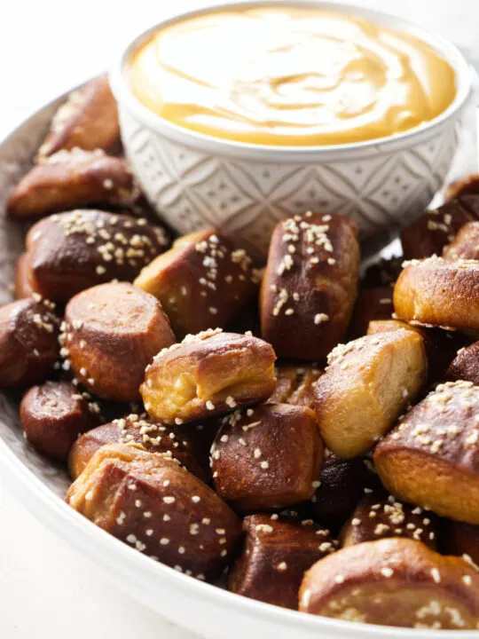 A plate filled with beer pretzel bites and cheese sauce.