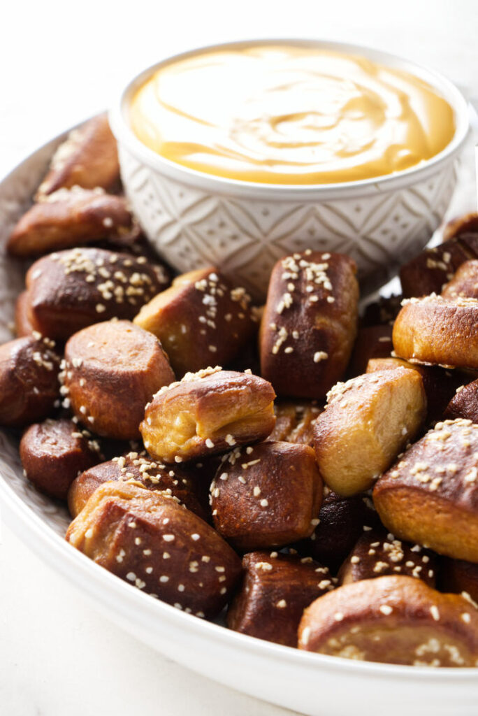 A plate filled with beer pretzel bites and cheese sauce.