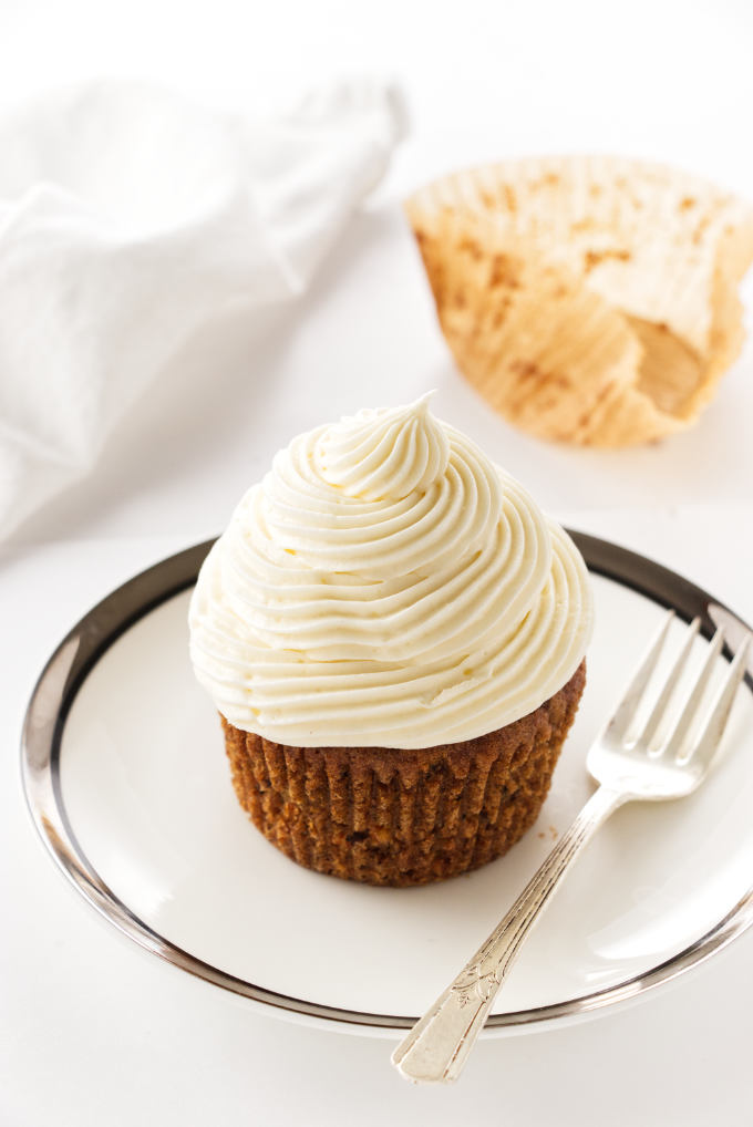 Overhead view of a serving of carrot cake cup cake with paper wrapper in the background