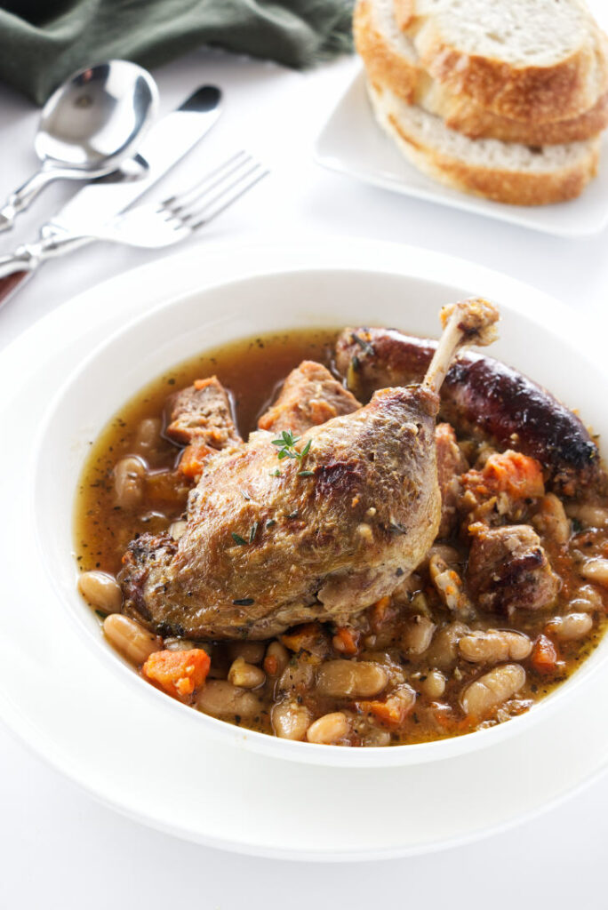 A serving of cassoulet topped with a duck leg
