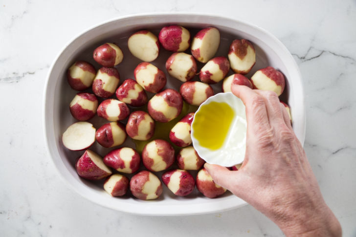 Coating baby potatoes with olive oil.