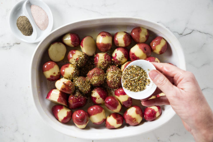 Adding seasoning to baby potatoes.