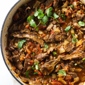 A large skillet with steak ranchero topped with cilantro.