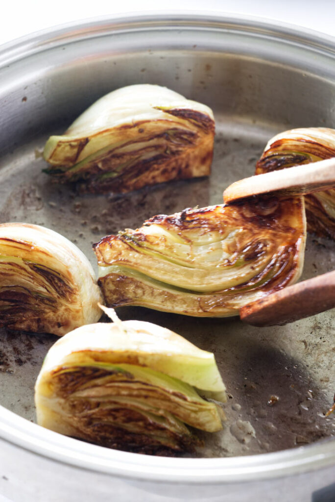 Turning wedges of fennel in a hot skillet.