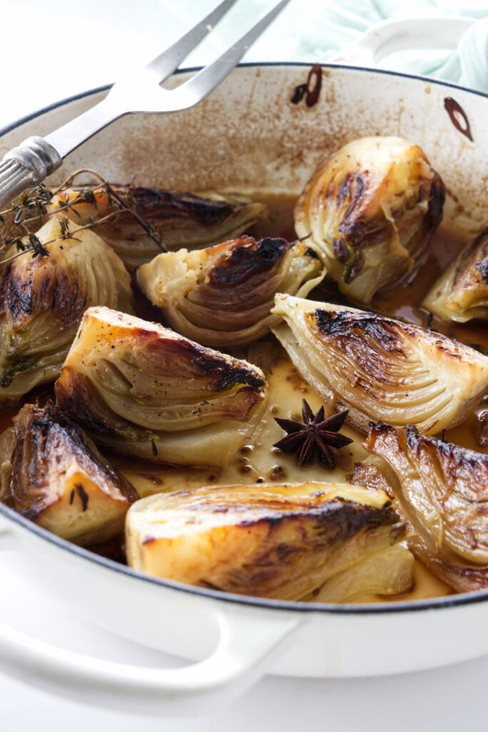 A serving fork on a skillet of braised fennel.