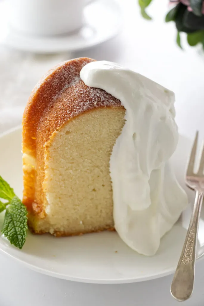 a slice of cold oven lemon pound cake on a plate with whipped cream