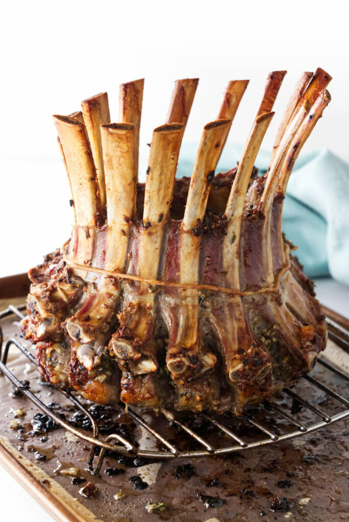 A roasted crown rack of lamb on a baking sheet.