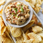 A serving dish with smoked gouda dip and potato chips.