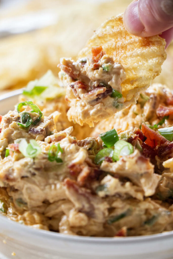 dipping a chip into a bowl of smoked gouda dip.