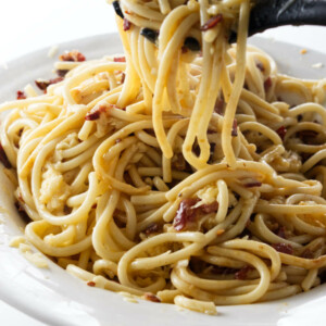 Lifting pasta out of a dish of carbonara.