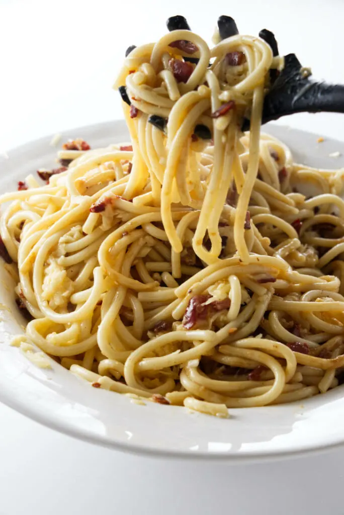 Lifting pasta out of a dish of carbonara.