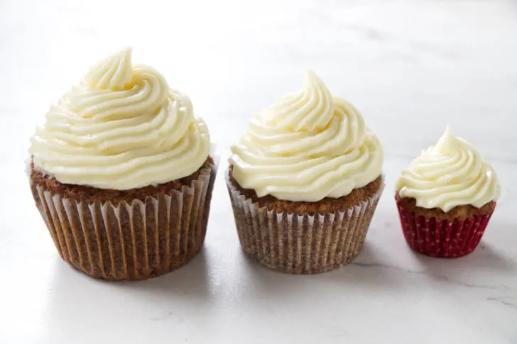 Three carrot cake cupcakes in different sizes.