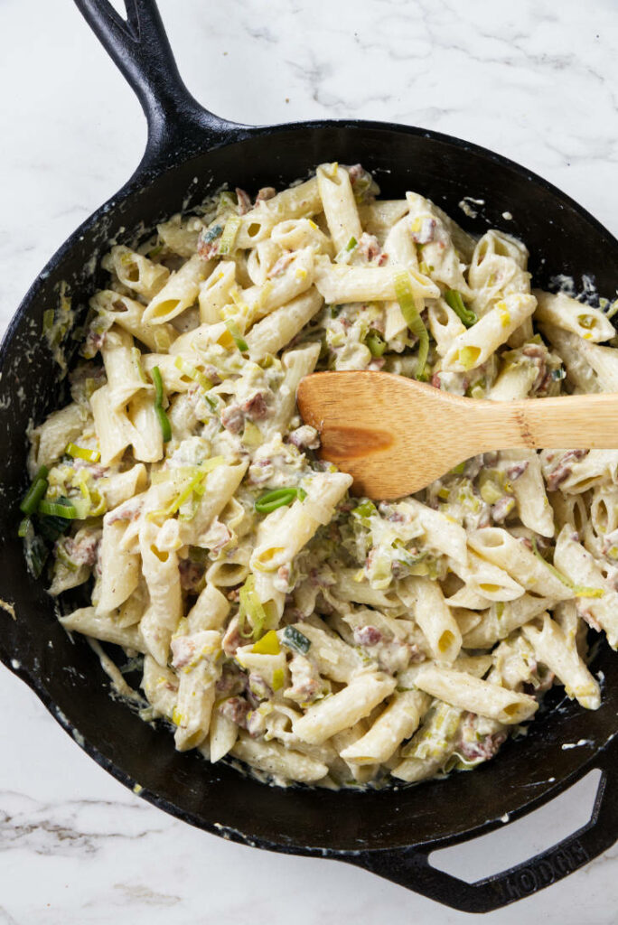Leek and bacon pasta in a skillet.