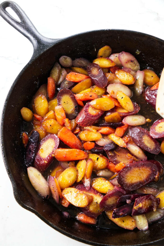 Glazed rainbow carrots in a skillet.