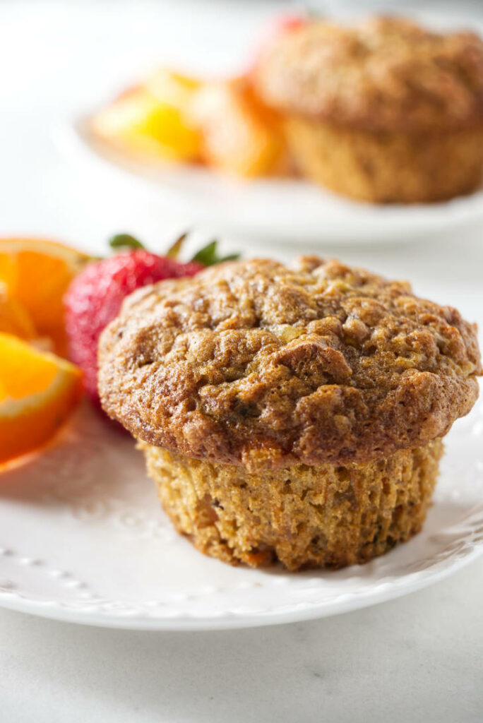 A muffin on a breakfast plate with fruit.