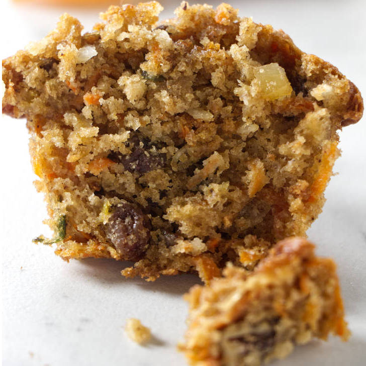 A muffin cut in half to show the carrots, apples, and raisins.