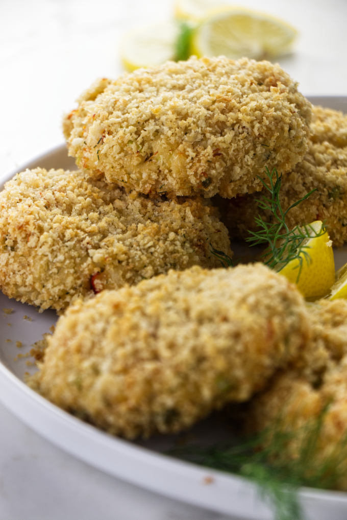 Several panko breaded crab cakes on a plate.