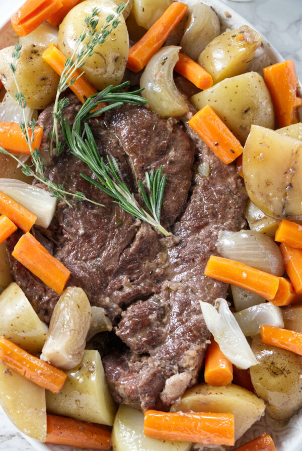 A serving dish filled with pot roast and vegetables.