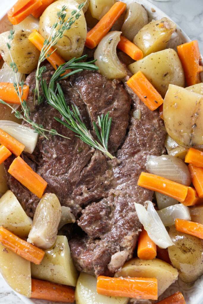 A serving dish filled with pot roast and vegetables.