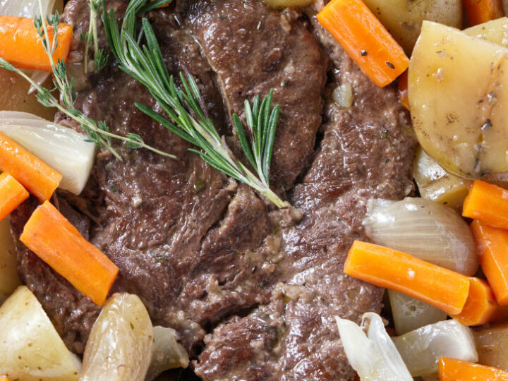 A serving dish filled with pot roast and vegetables.