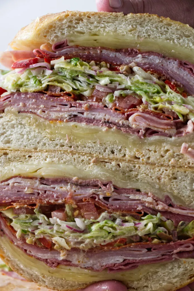 https://savorthebest.com/wp-content/uploads/2022/05/Italian-grinder-salad-sandwich-sliced-open_2216-683x1024.jpg.webp