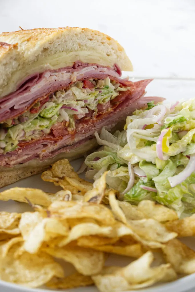 A grinder sandwich with chips and a salad.