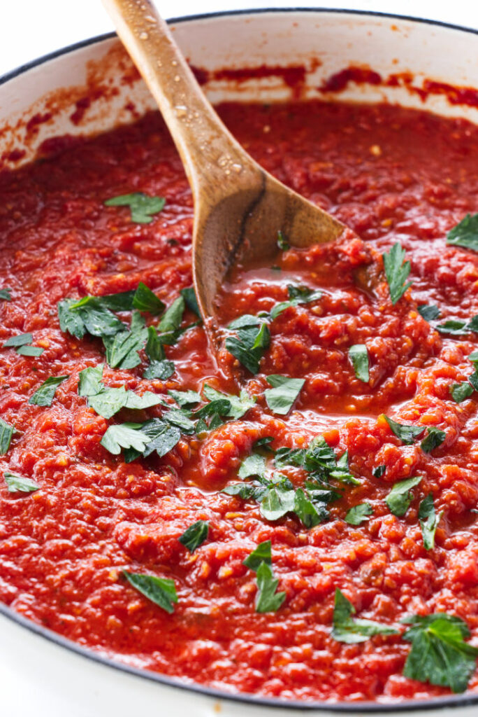 A spoon scooping up tomato sauce.