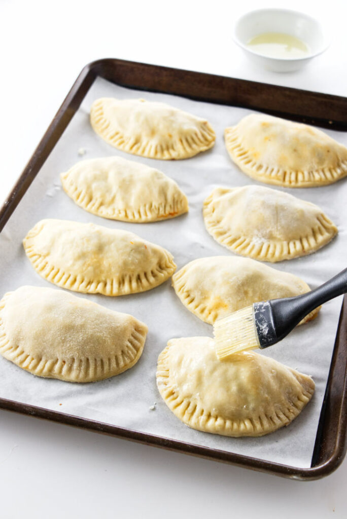 empanadas being brushed with egg wash