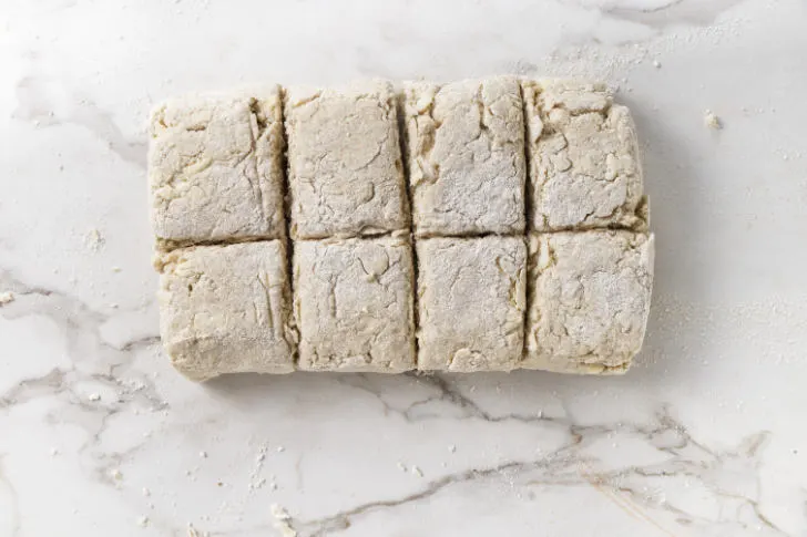Slicing biscuit dough into squares.