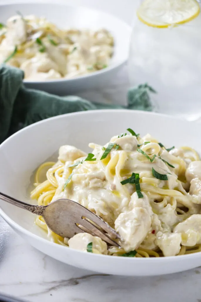 Two bowls of garlic butter pasta with chicken.
