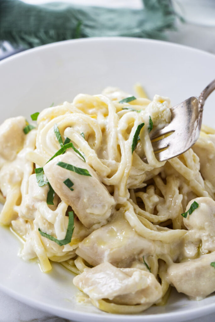 A fork scooping up some creamy pasta.