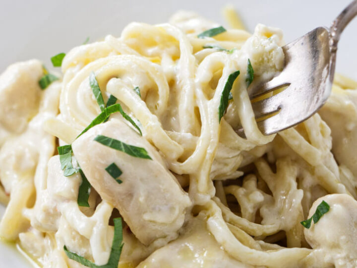 A fork scooping up some creamy pasta.