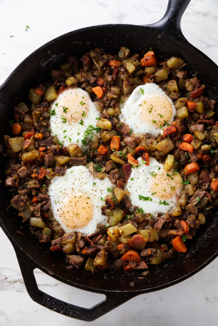 Beef and potato hash in a skillet with eggs on top.