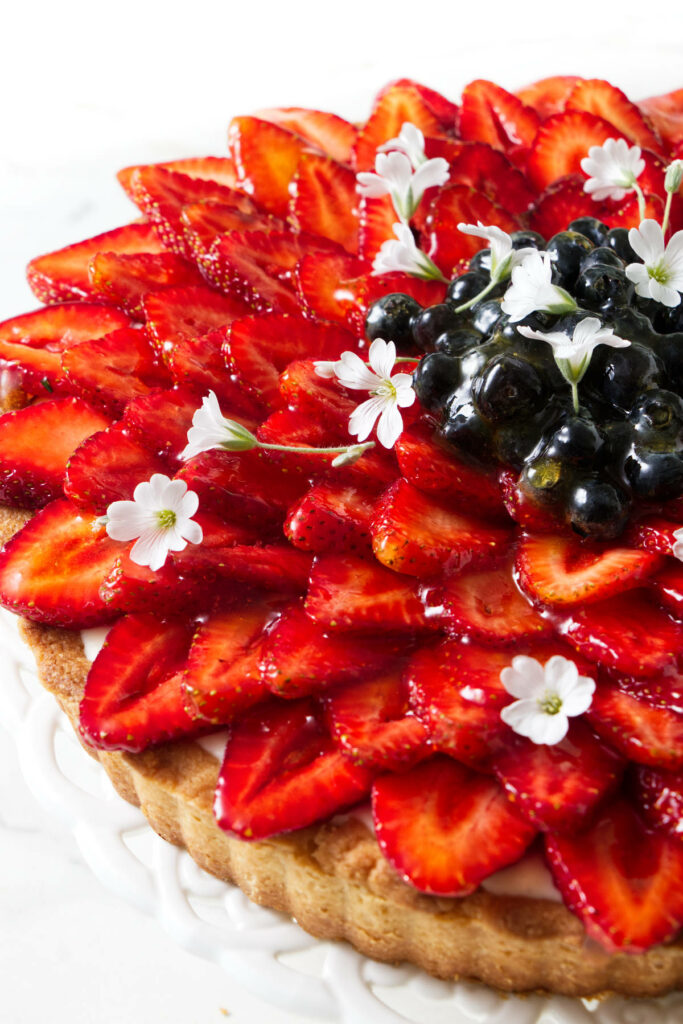 A fruit tart with sliced strawberries and blueberries on top.