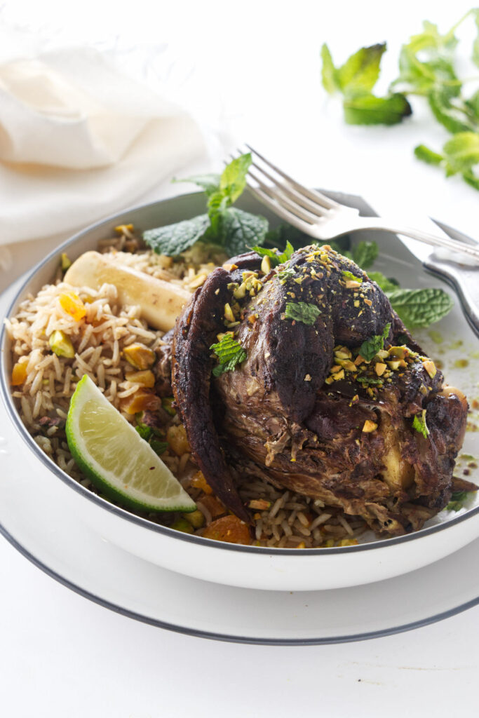 A serving of Persian Lamb Shank with rice pilaf, mint and lime wedge