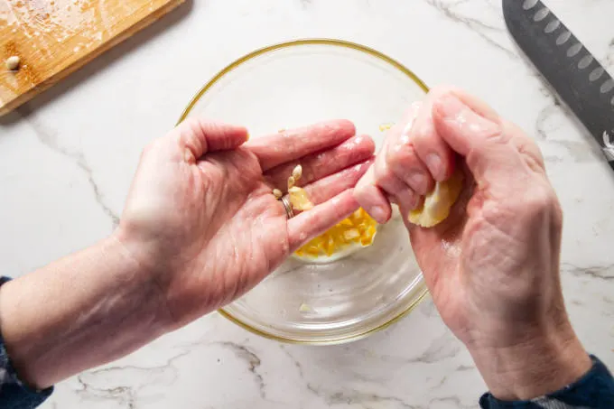 Squeezing lemon juice over a hand to catch the seeds.