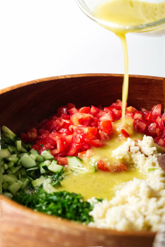 Pouring dressing over a tabbouleh salad.