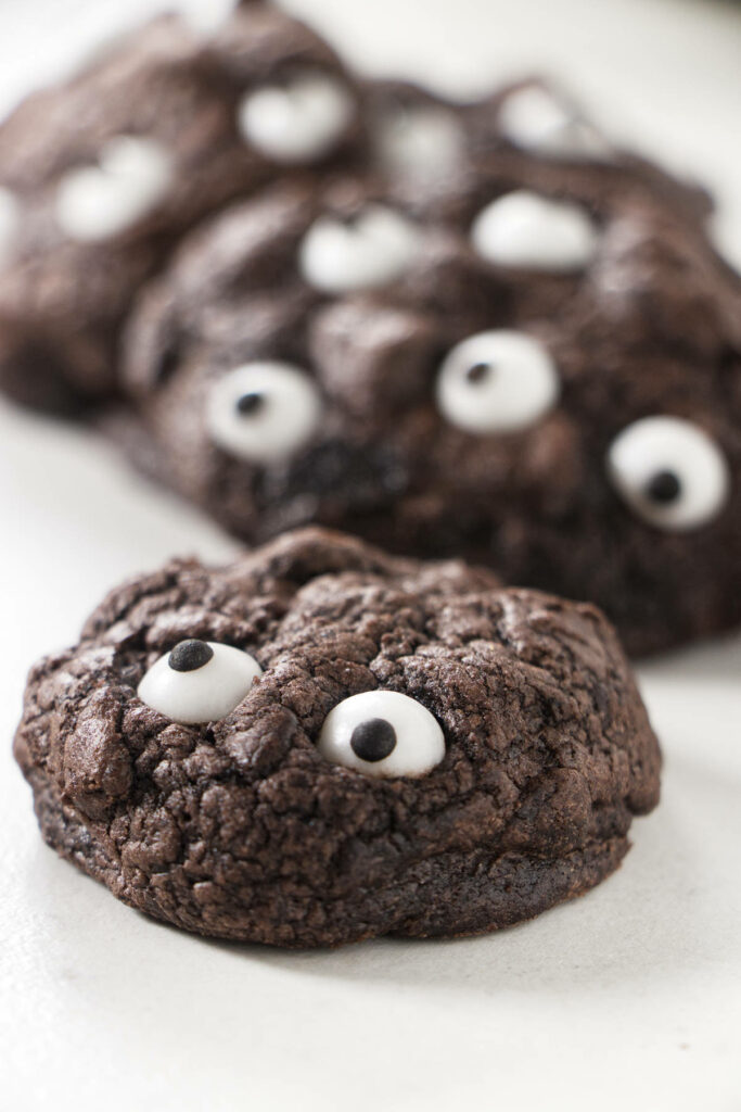 Black cocoa cookies with candy eyes on top.