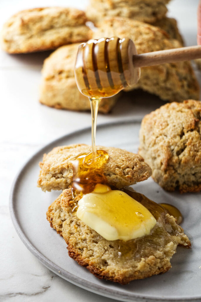 Drizzling honey on a biscuit.