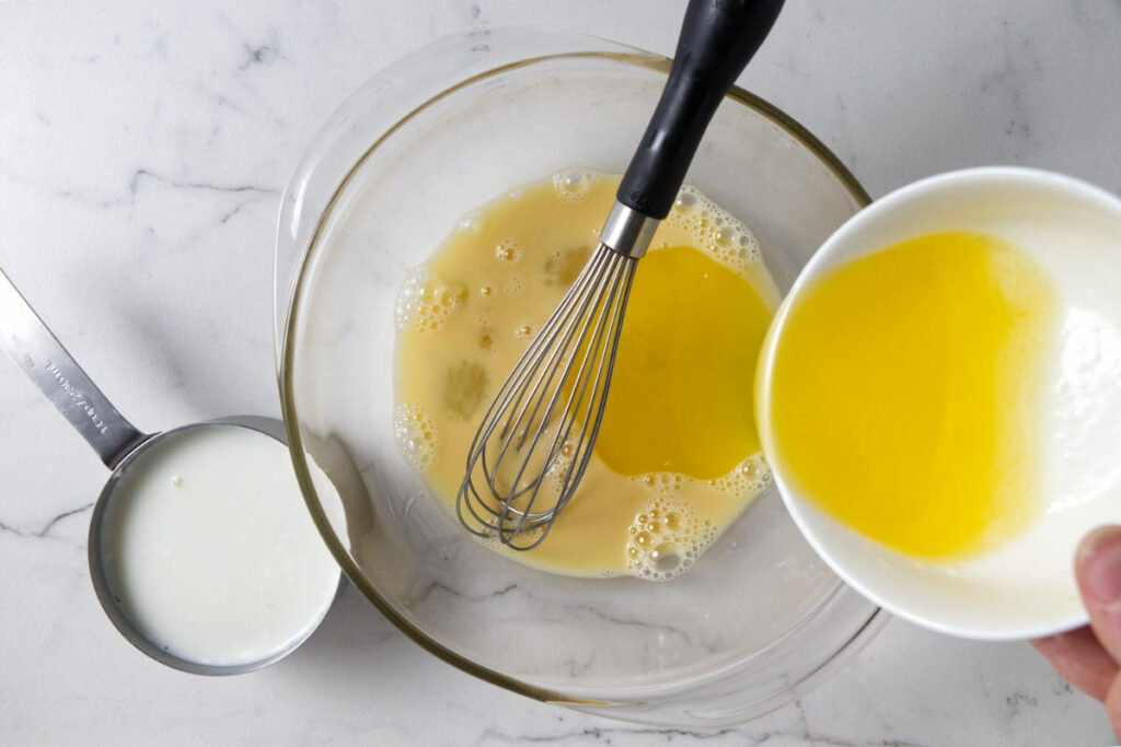 Adding melted butter to cornbread batter.