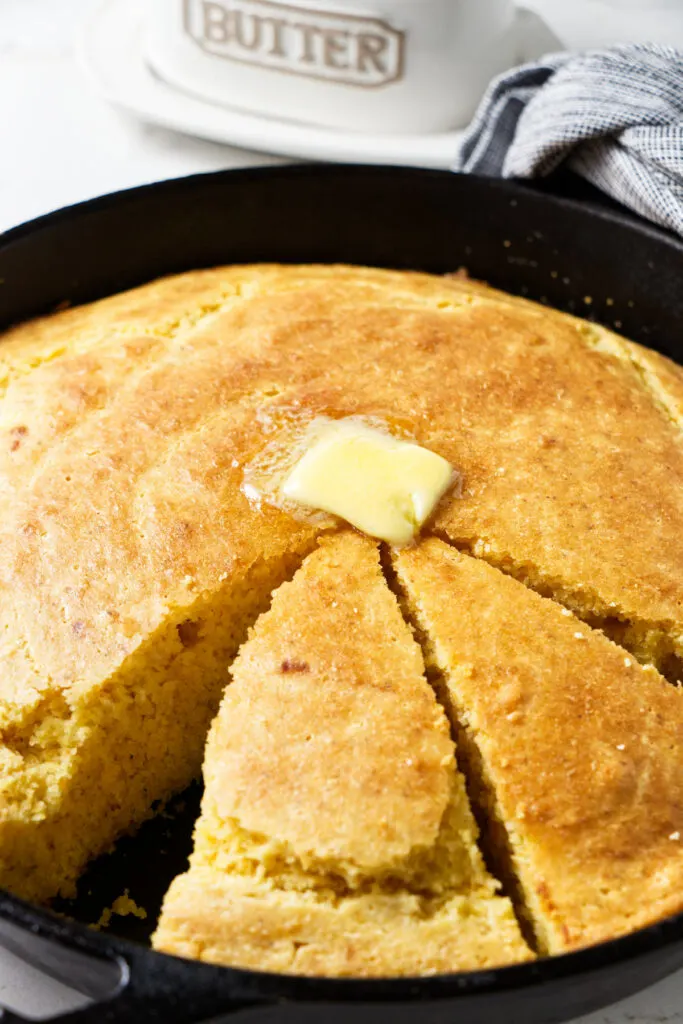 Slices of cornbread in a skillet with butter.
