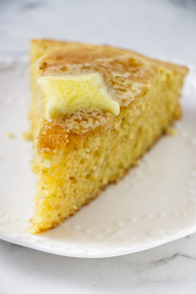 A slice of cornbread with melting butter on top.