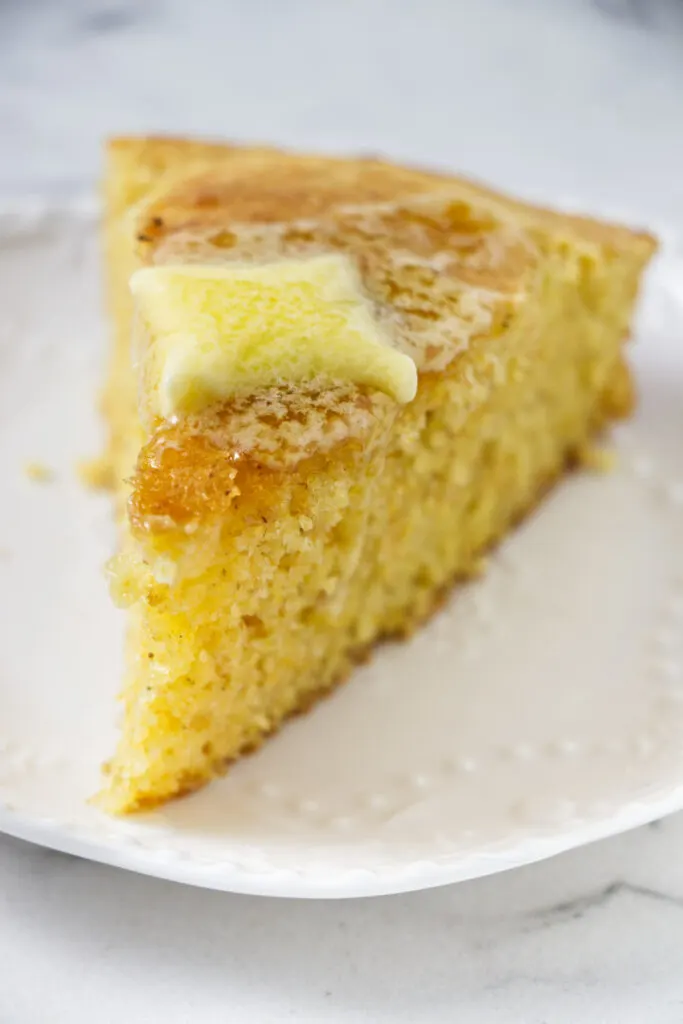 A slice of cornbread with melting butter on top.