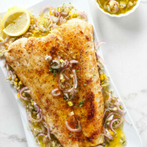 Smoked sea bass on a serving platter with lemon sauce.